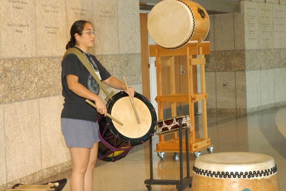 Woman demonstrates with a drum slung across her body